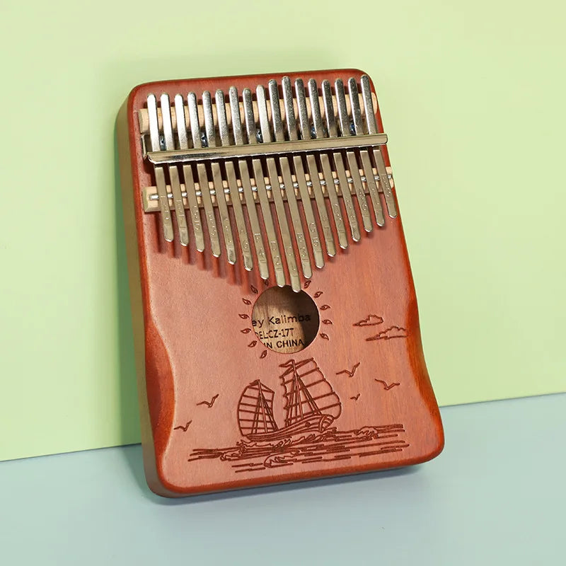 Red wooden kalimba finger piano with 21 silver metal tines and engraved sailing ship musical instrument mbira