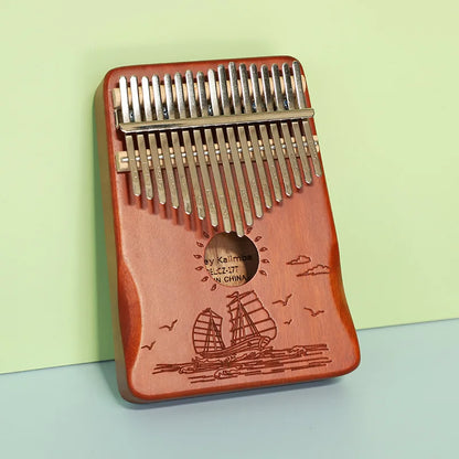 Red wooden kalimba finger piano with 21 silver metal tines and engraved sailing ship musical instrument mbira