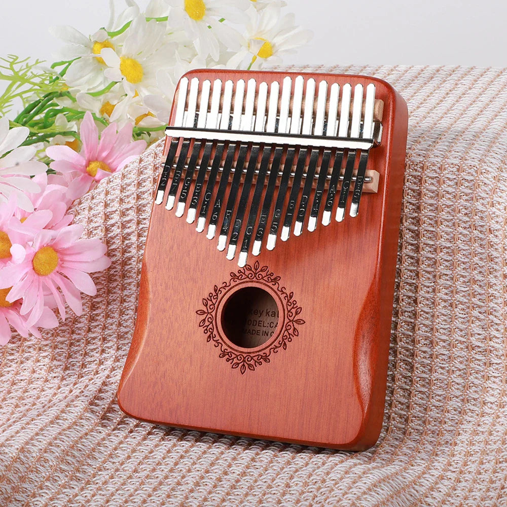 A polished reddish-brown wooden kalimba finger piano with 21 black and silver tines and ornate circular engraving musical instrument mbira