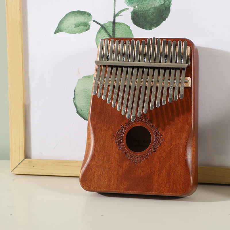 A polished reddish-brown mahogany wood kalimba music instrument thumb piano with silver metal tines and decorative sound hole
