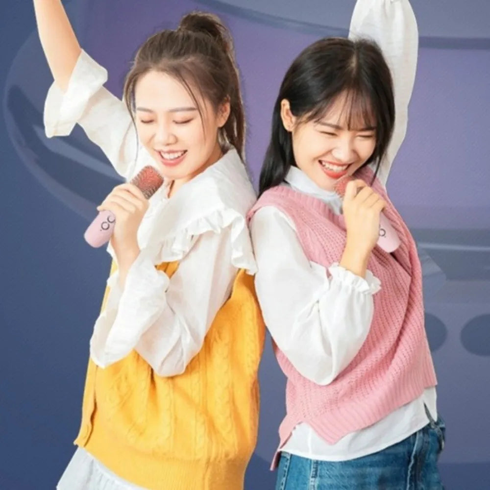 Pink and yellow knitted sleeveless vests worn over white shirts beside a karaoke machine mini with wireless dual microphones and projector night light
