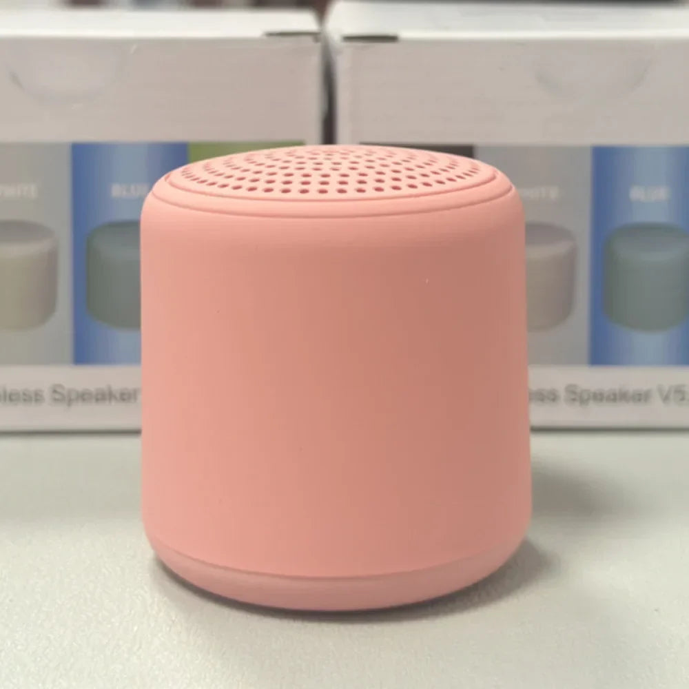 A soft pink cylindrical karaoke mini bluetooth speaker with a matte finish and perforated top for rechargeable music wireless use
