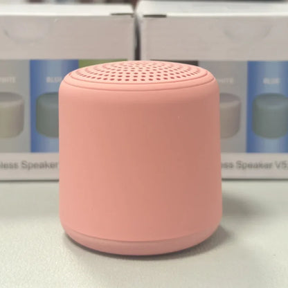 A soft pink cylindrical karaoke mini bluetooth speaker with a matte finish and perforated top for rechargeable music wireless use