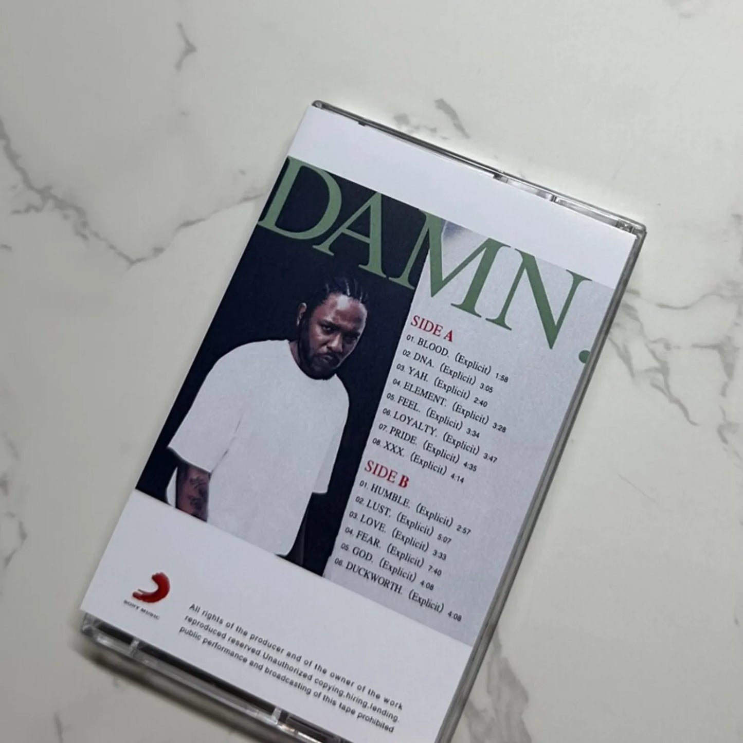A clear plastic cassette tape case containing kendrick lamar damn album with black and white cover for hip hop rap fans