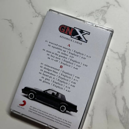 Clear plastic hip hop rap cassette tape with white label black text kendrick lamar gnx album and classic car illustration