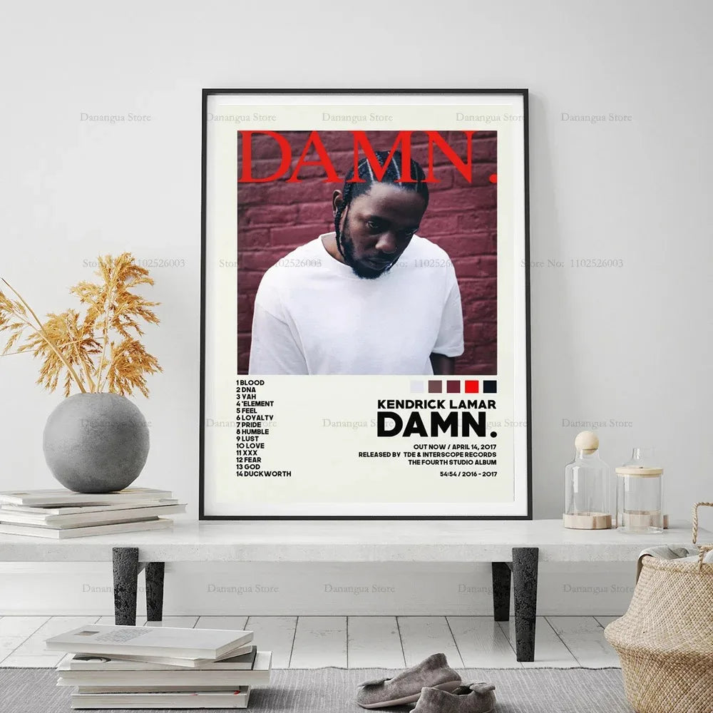 Black-framed kendrick lamar damn album cover poster with bold red lettering and white t-shirt on brick wall background