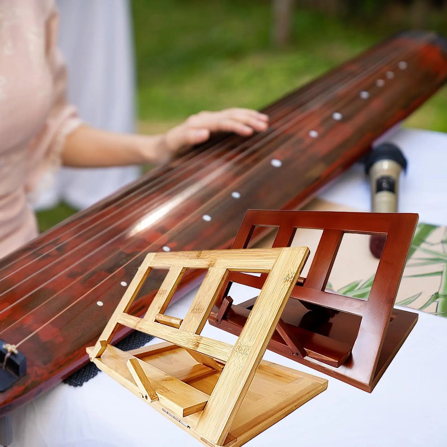 A sleek dark reddish-brown guqin beside two foldable bamboo keyboard music score stands for music sheet display