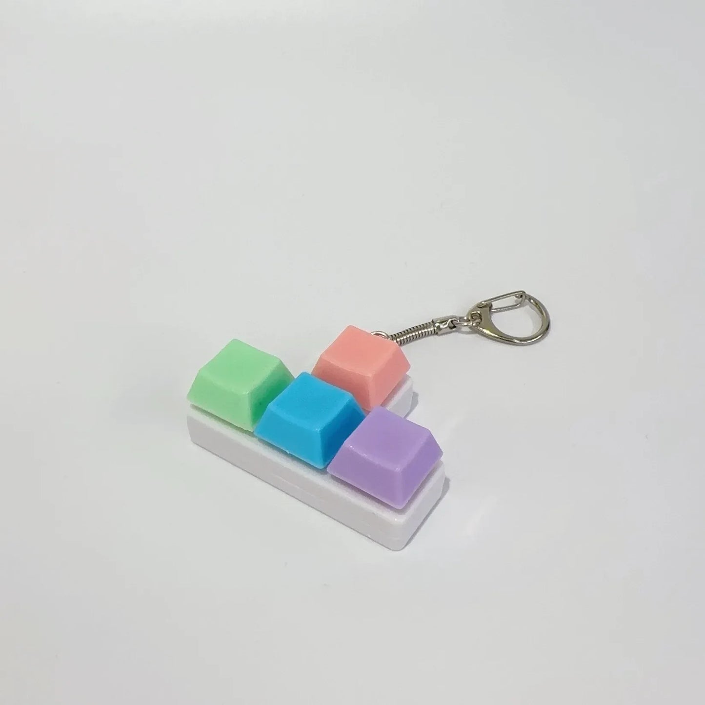 A colorful keychaintoy press stress relief fidget button keychain with translucent green, blue, pink, and purple keys on white base