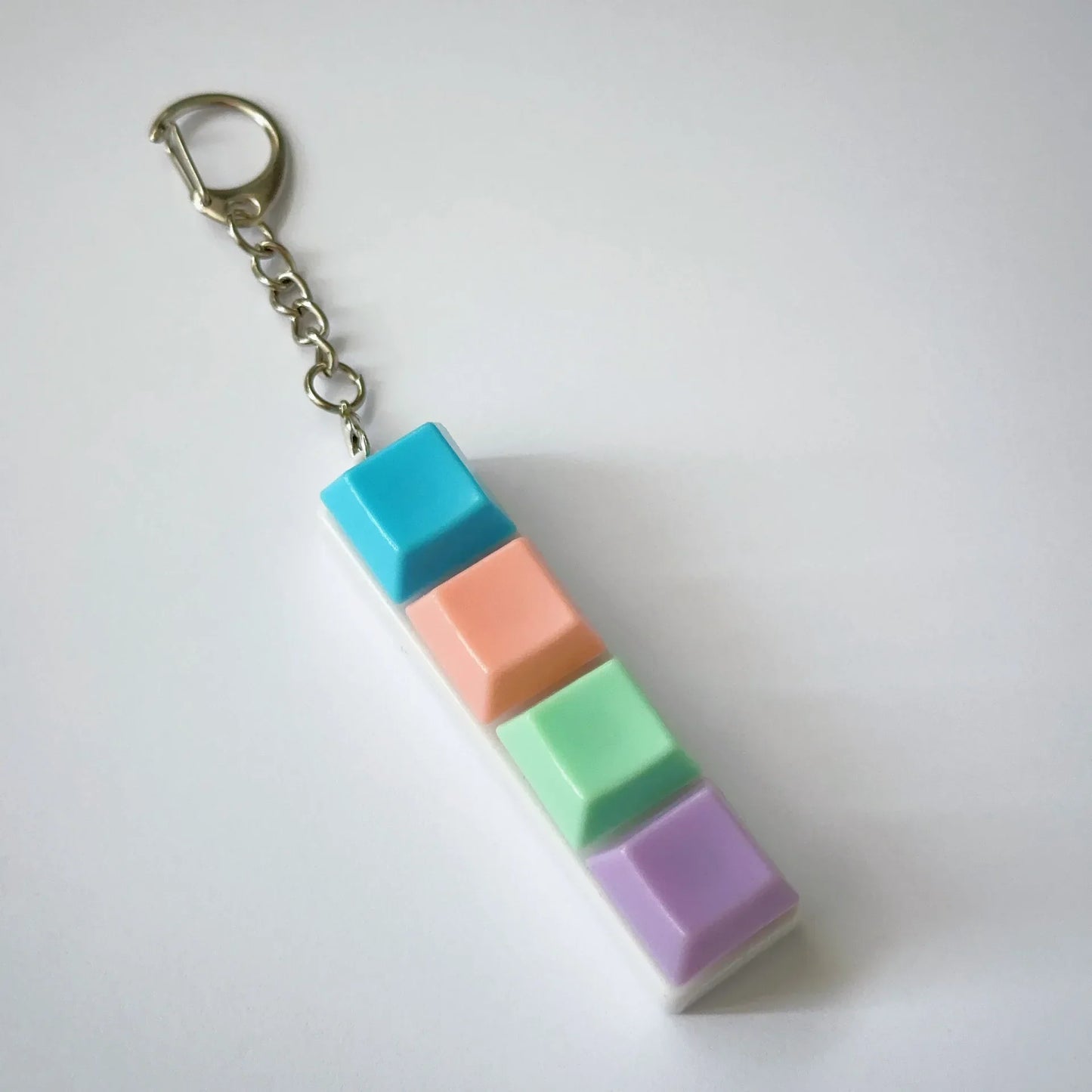Pastel-colored keychaintoy press stress relief fidget button keyboard keychain toys with four stacked keycaps in turquoise peach mint and lavender