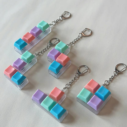 Pastel-colored keyboard keychain toys with translucent plastic bases and metallic chains for keychaintoy press stress relief fidget button use