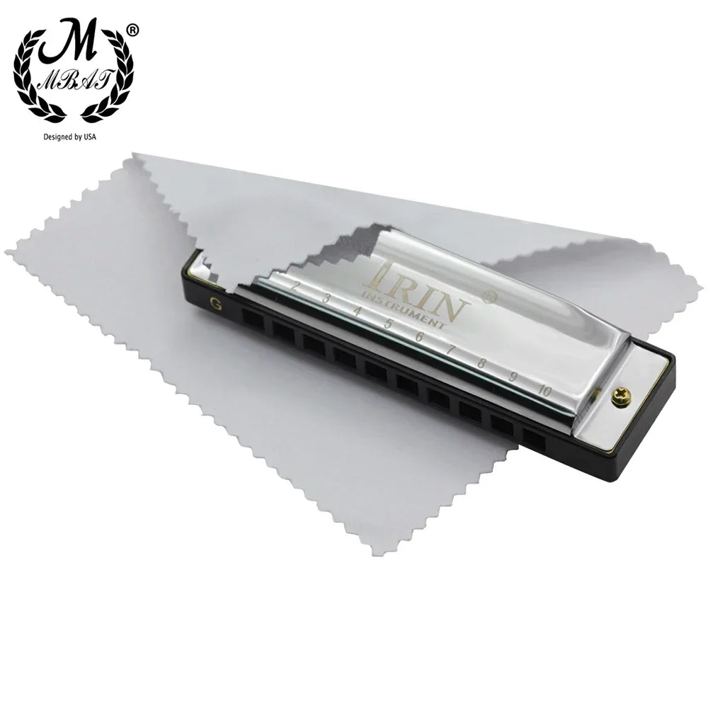 Silver-toned m mbat blues harmonica with abs box, black plastic body, and gold tuning pin on white microfiber cloth
