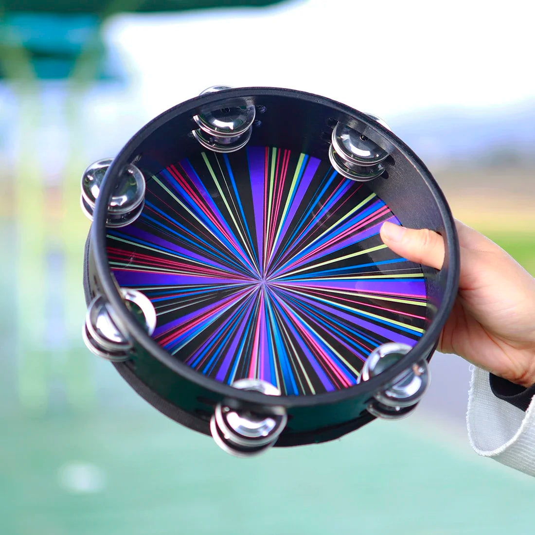 A vibrant rainbow-colored 8 inch tambourine handbell hand with black frame and chrome jingles for musical use