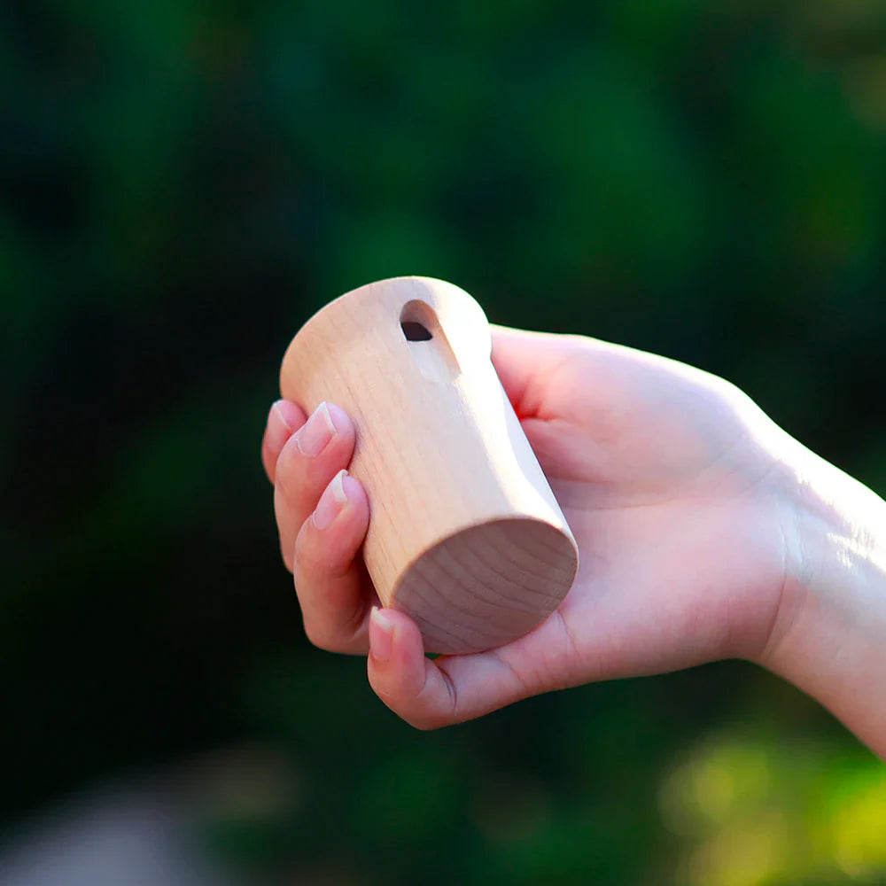 A smooth light-colored wooden mbat orff musical sound whistle kids educational toy with rounded top and hanging hole