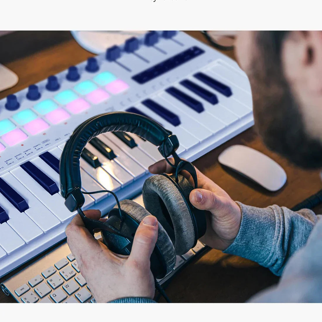 Black over-ear headphones with padded textured earcups and adjustable hinges paired with usb midi controller rgb pads knobs supports software
