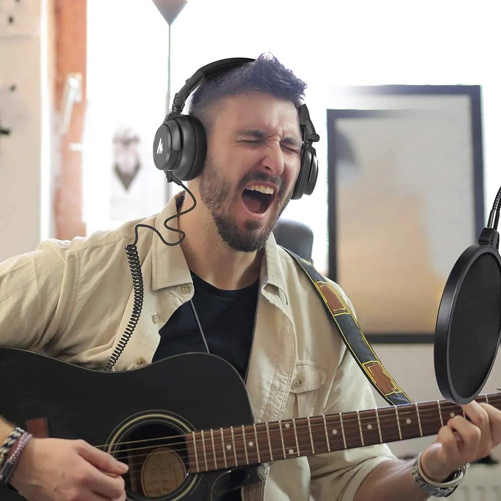 Black acoustic guitar with wooden fretboard played indoors next to maono mh601 professional studio monitor headphones with detachable plug
