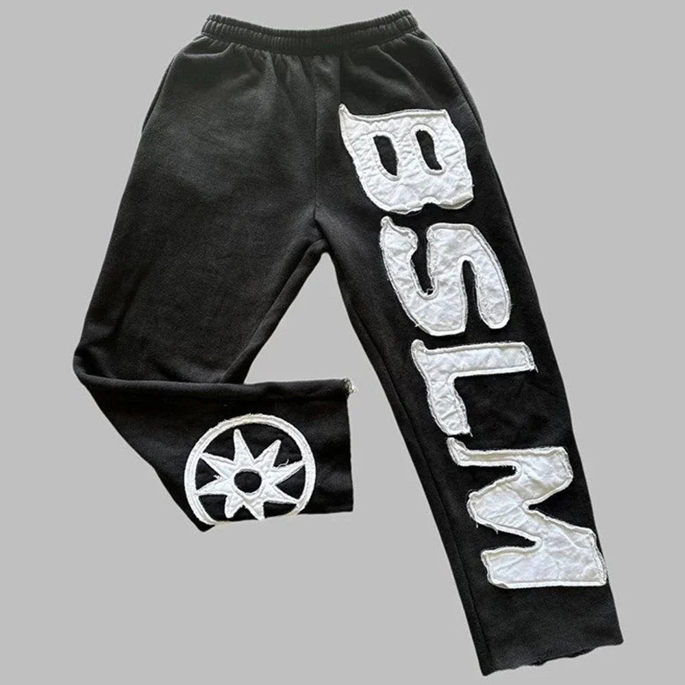 Black velour sweatpants with bold white letter embroidery fashion and circular star emblem for street style harajuku look