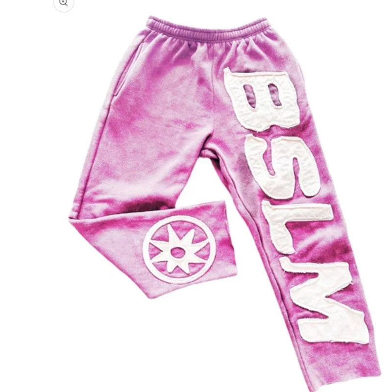 Pink velvet sweatpants with white letter embroidery fashion and circular sunburst logo for street style harajuku wear