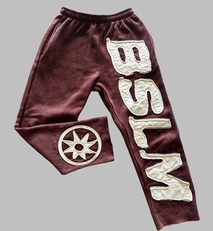 Maroon velour sweatpants with quilted cream letter embroidery and circular star emblem for street style harajuku fashion
