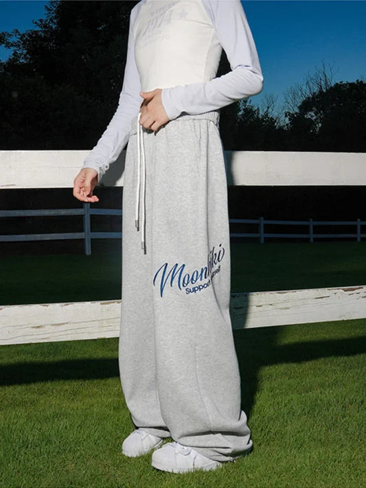 Men’s y2k streetwear baggy gray sweatpants with printed blue moonkai logo and supportive text in hip hop fashion style