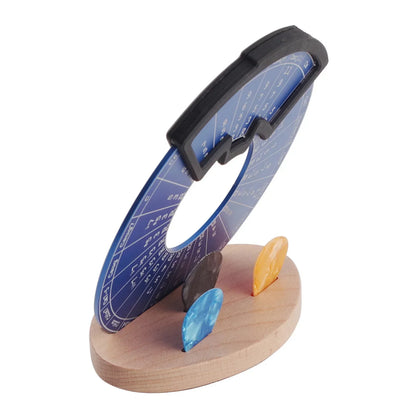 Metal fifths wheel with blue circular chart and three colorful gemstone markers on wooden stand for theory learning tool