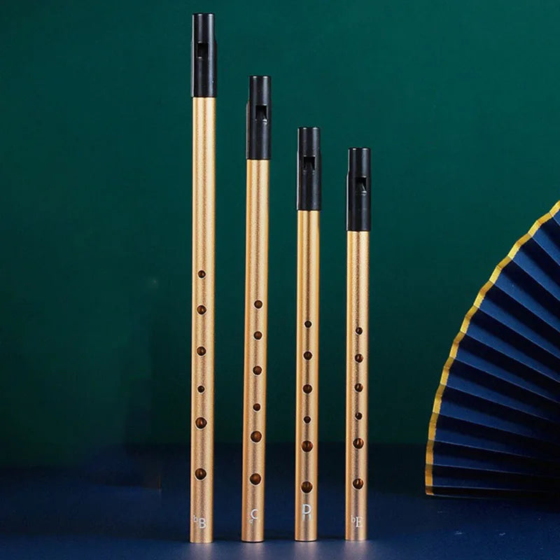 Four brass-colored metal Irish whistles with black mouthpieces engraved for professional performance and student playing recorder