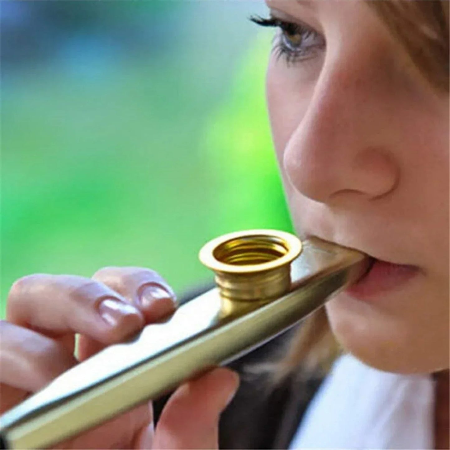 Gold-colored metal kazoo accompaniment with shiny metallic finish and circular mouthpiece for guitar ukulele beginner use