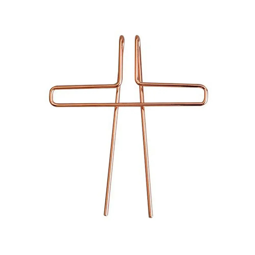 Copper-colored metal music book clip in a wire cross shape serving as a page holder for pianos and cooking recipe magazines