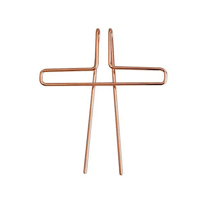 Copper-colored metal music book clip in a wire cross shape serving as a page holder for pianos and cooking recipe magazines