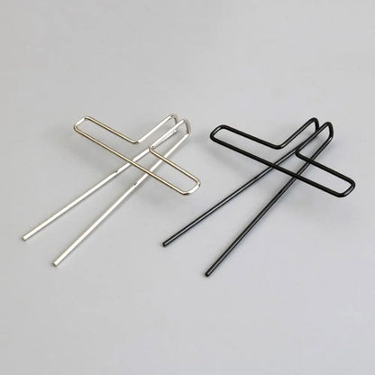 Two minimalist metal music book clips in polished silver and matte black with cross-shaped design for page holder pianos and cooking recipe magazines