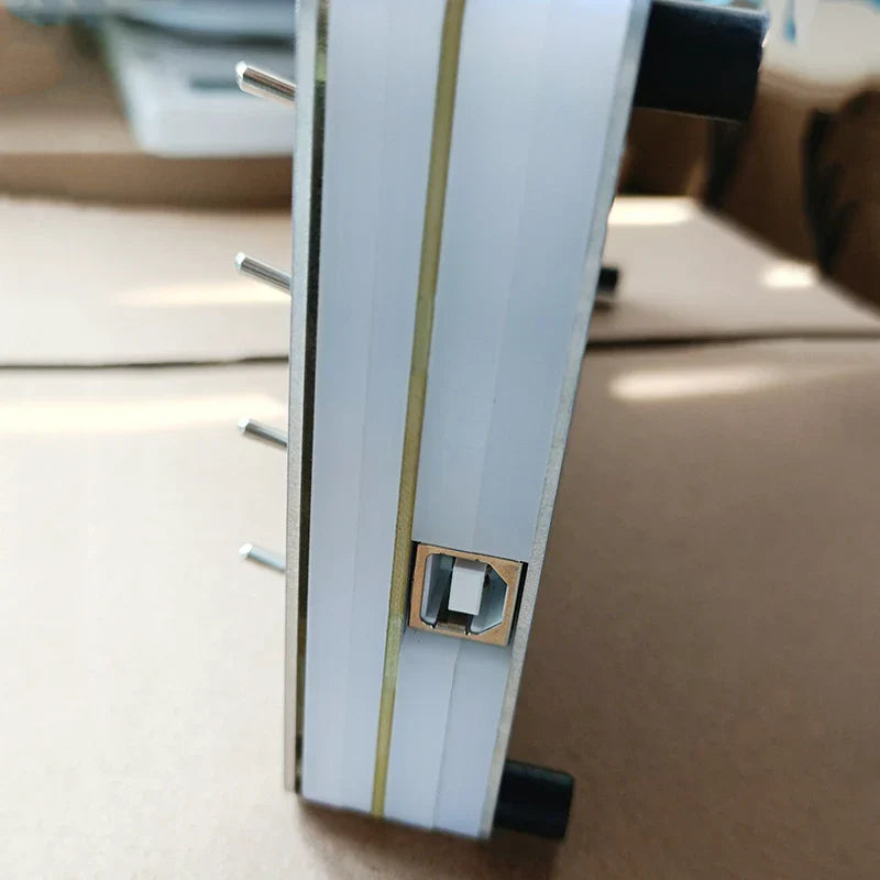 White and gold-framed midi cc controller with sliding fader usb port on side for computer music hosting software use