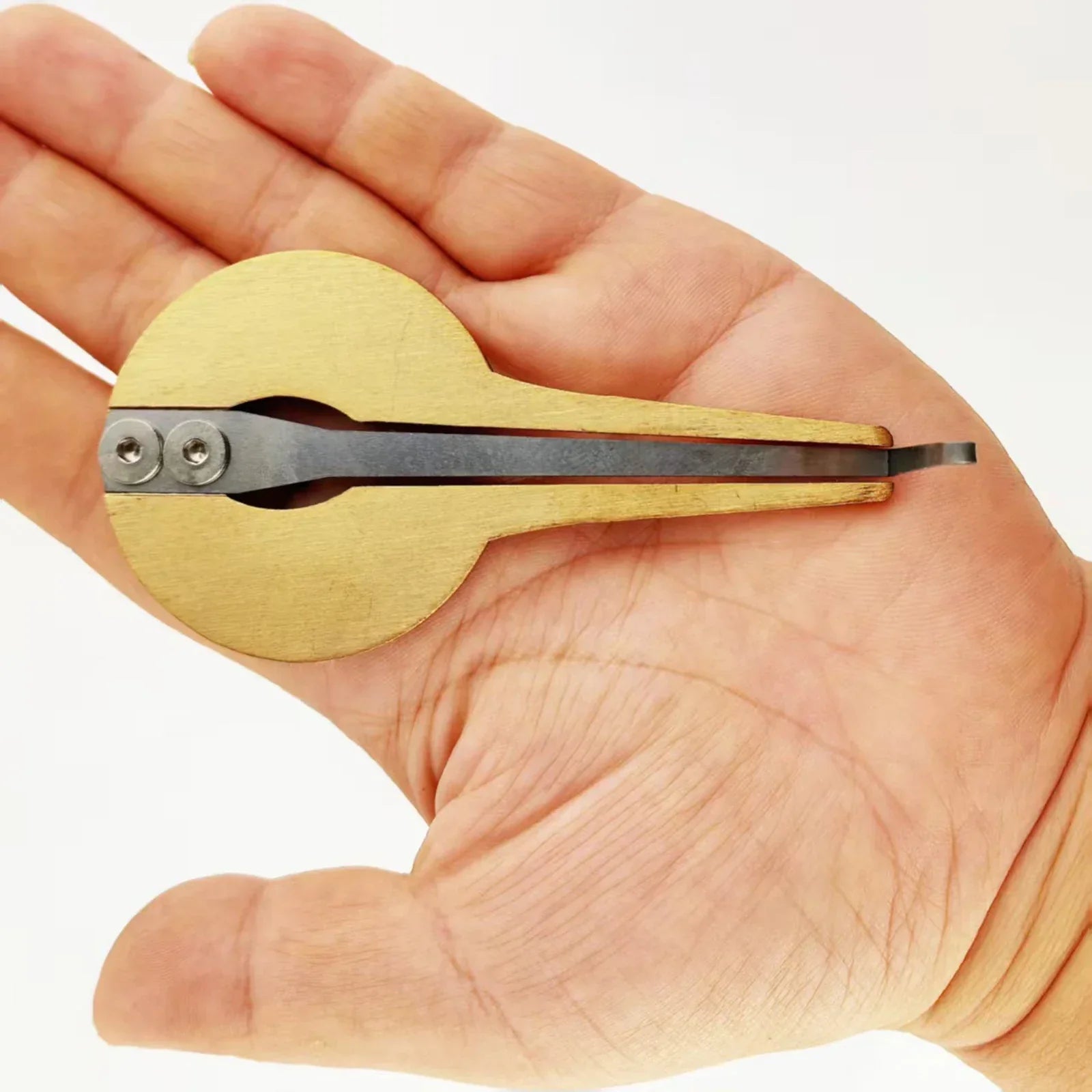 A light-colored wooden jaw harp beginner with a dark metal reed and two silver screws mouth music instrument