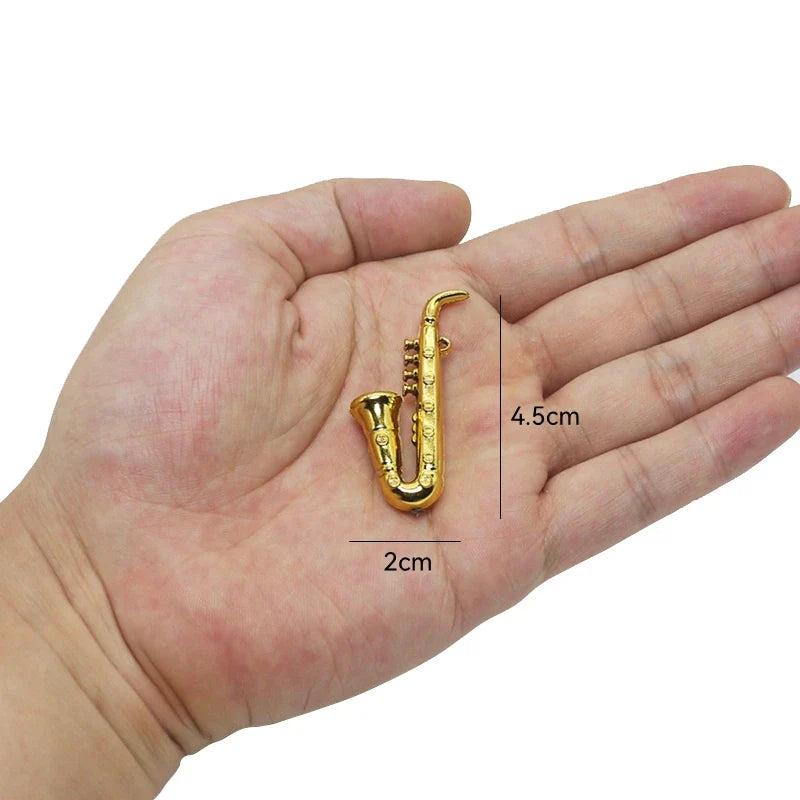 Gold-colored miniature musical instruments saxophone pin with intricate key details and polished metallic finish accessory