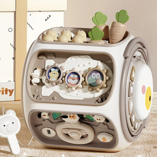 Beige and white montessori sensory toy cube with cartoon animal buttons steering wheel and carrot inserts for children cognitive development and color sorting