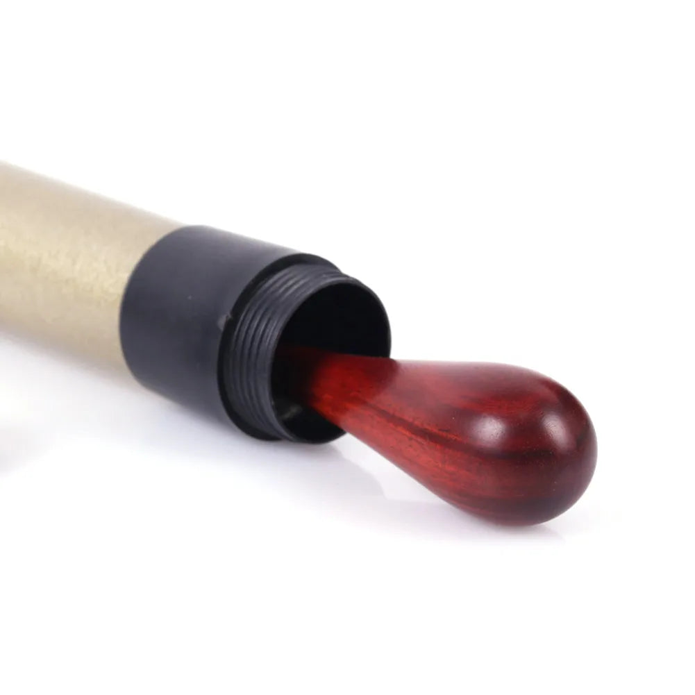 A polished deep red concert conducting rosewood music wand orchestra applicator emerging from a metallic tube