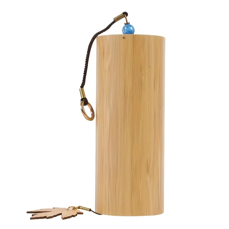 A light brown bamboo wind handbell with a black cord blue bead gold ring and wooden maple leaf charm for refined meditation bells
