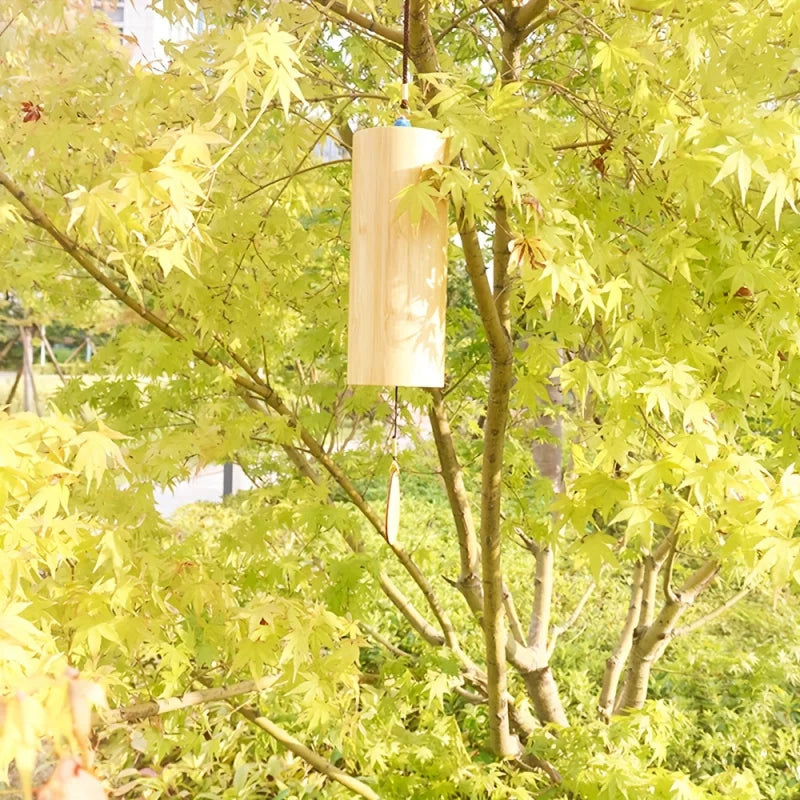 A light-colored bamboo wind handbells yoga chime hanging from a tree branch for refined meditation bells creating melodies