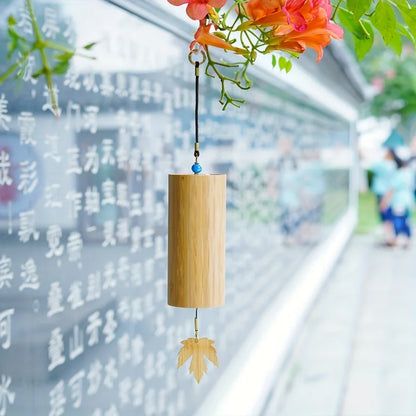 A natural bamboo wind handbell with a tan finish blue bead and maple leaf charm for refined meditation bells creating melodies