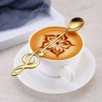 Golden stainless steel musical note spoon shaped like treble clef resting in white coffee cup with latte art for mug teaspoons music and ice cream creative use