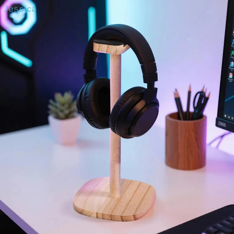 A sleek black gaming over-ear headphone rests on a natural wood headphone stand with a stable slatted base