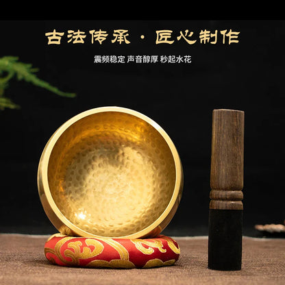 Golden hammered buddha sound bowl made of brass resting on red and gold cushion with wooden mallet for sound bowl yoga