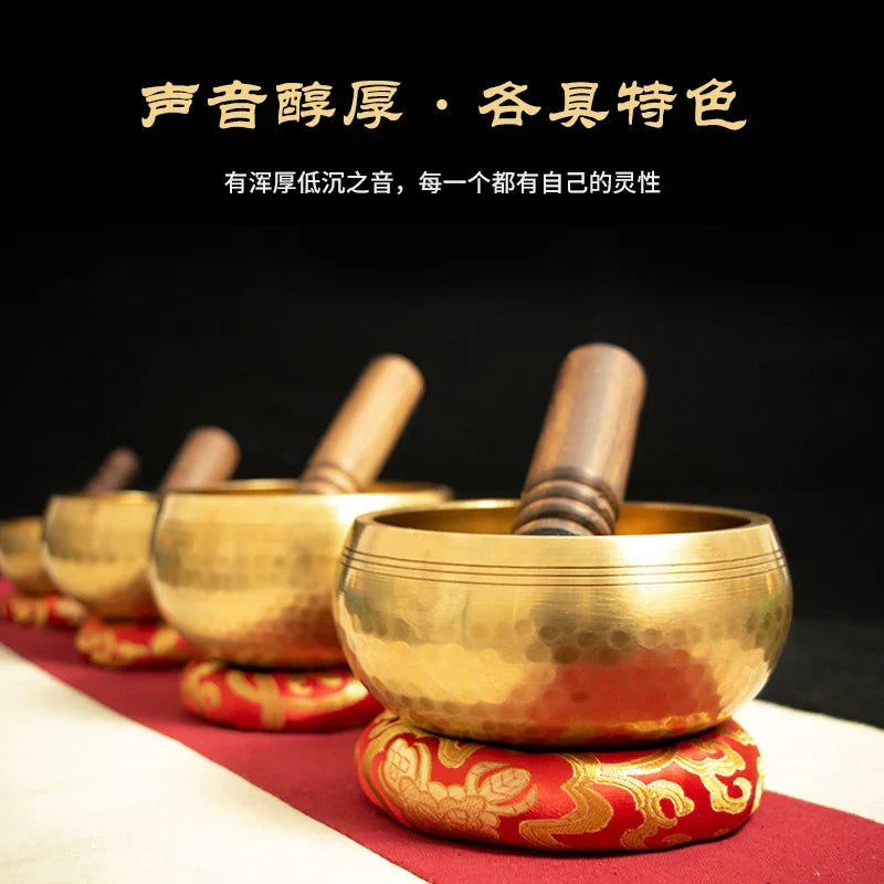 Golden nepali handmade buddha sound bowls with wooden mallets on red and gold cushions for sound bowl yoga and brass chime therapy