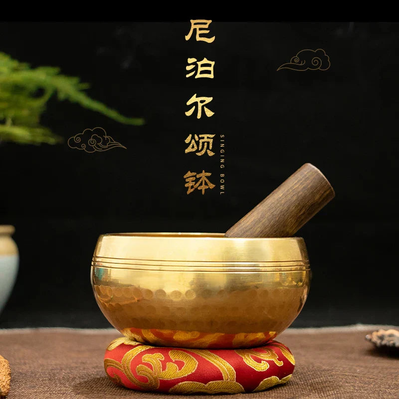 Golden tibetan buddha sound bowl with hammered brass texture resting on ornate red and gold cushion for sound bowl yoga