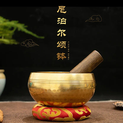 Golden tibetan buddha sound bowl with hammered brass texture resting on ornate red and gold cushion for sound bowl yoga