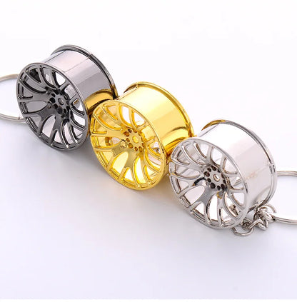Three 3d miniature car metal wheel rim keychains in chrome gold and silver finishes as a car key ring hub key chain