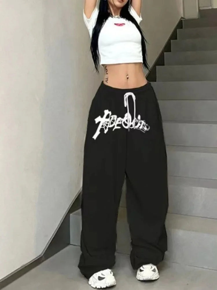 Black wide leg high waist hip hop jazz sweatpants with white graffiti style lettering and a drawstring waist