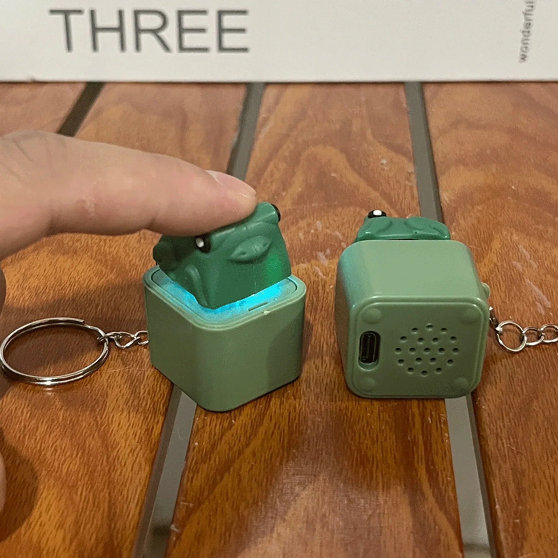 Green frog-shaped croaking frog keychain speaker with matte finish and glowing blue LED for keyboard fidget clicker use