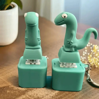 Teal dinosaur-shaped desk stapler with keychain attachment shown with croaking frog keychain keyboard fidget clicker features