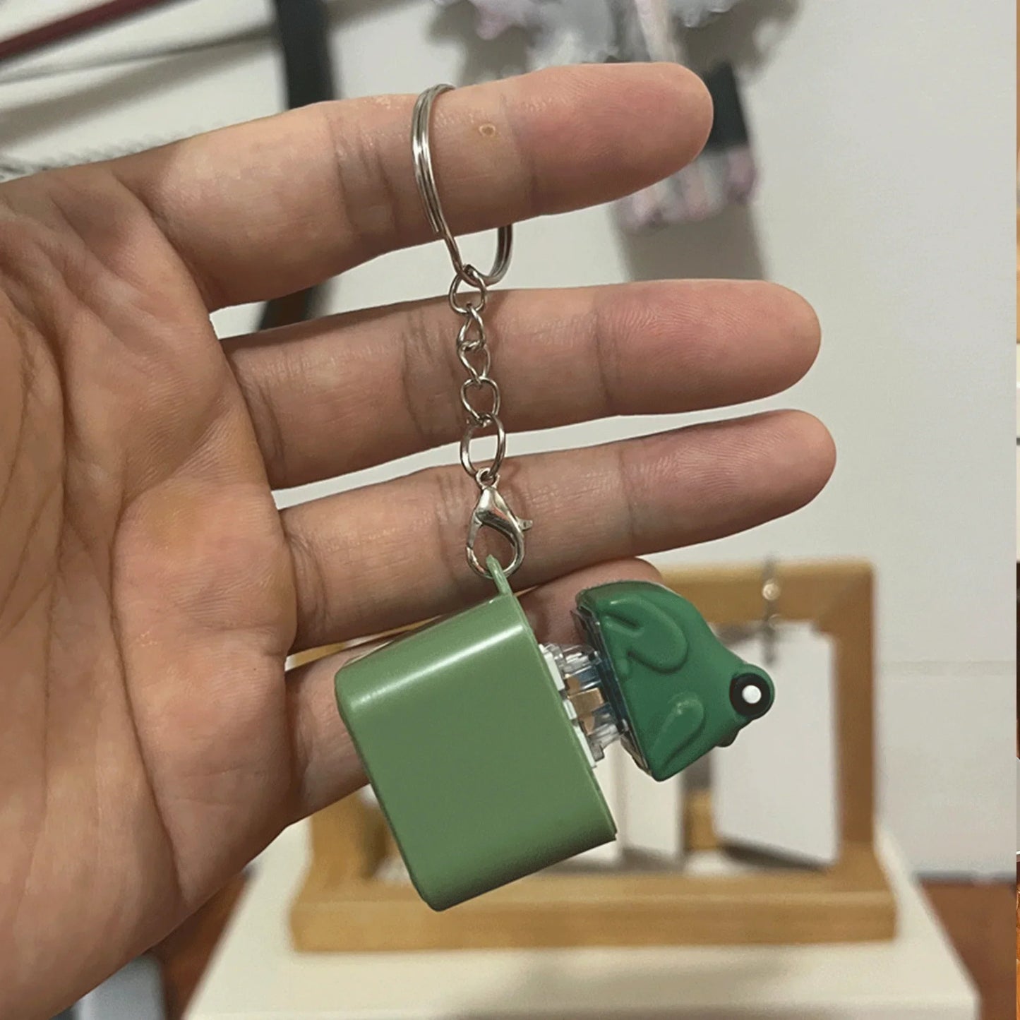 Green plastic croaking frog keychain with square compartment and metallic chain attachment for keyboard fidget clicker and frog lizard sound