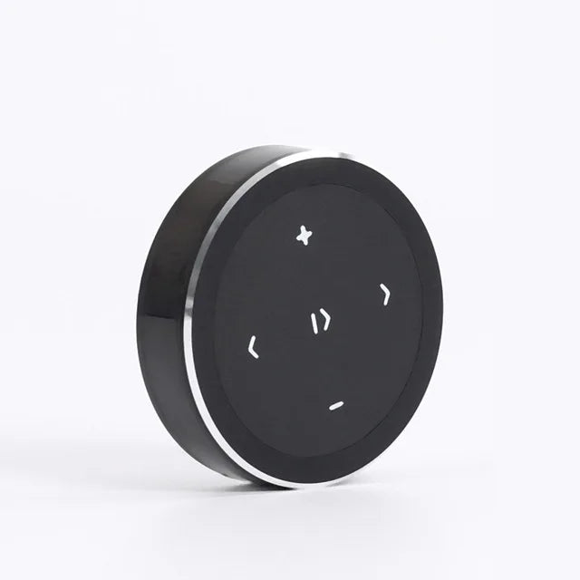 Black circular phone bluetooth music playback remote with silver metallic rim and white directional buttons for wireless use