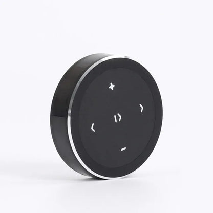 Black circular phone bluetooth music playback remote with silver metallic rim and white directional buttons for wireless use